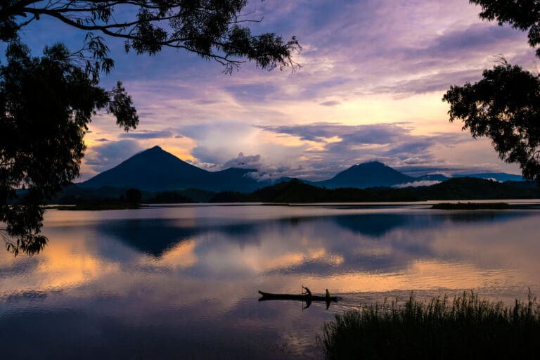 Lake Mutanda view with fishermen in canoe and purple skies during sunset