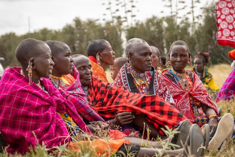 Gruppe von Maasai-Frauen in traditioneller Kleidung, die draußen sitzen